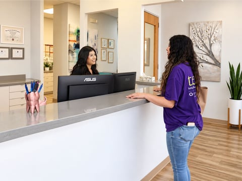 Aroma Dental team member welcoming a patient at the reception desk